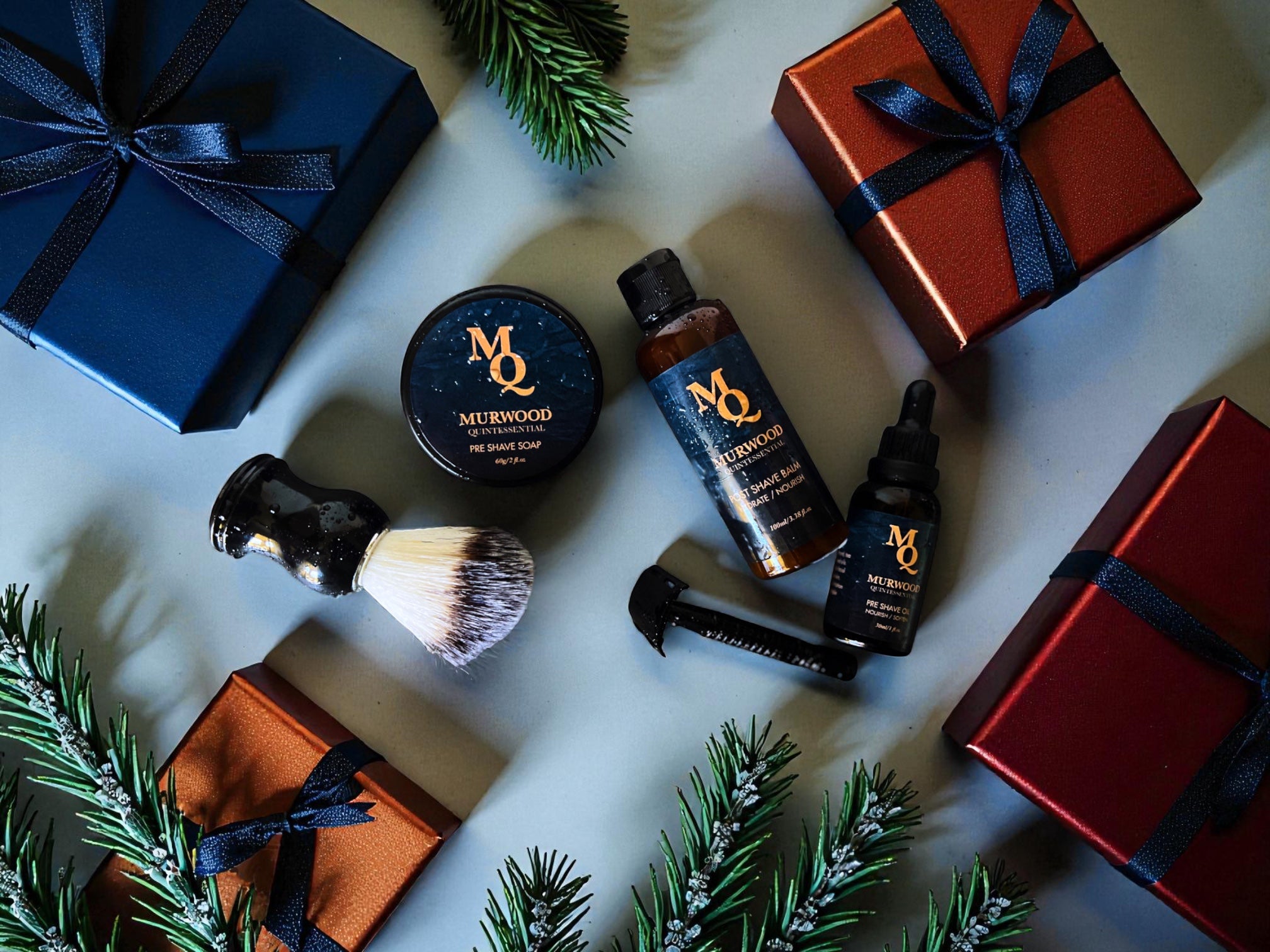 Grooming products and wrapped gifts on a light surface with greenery
